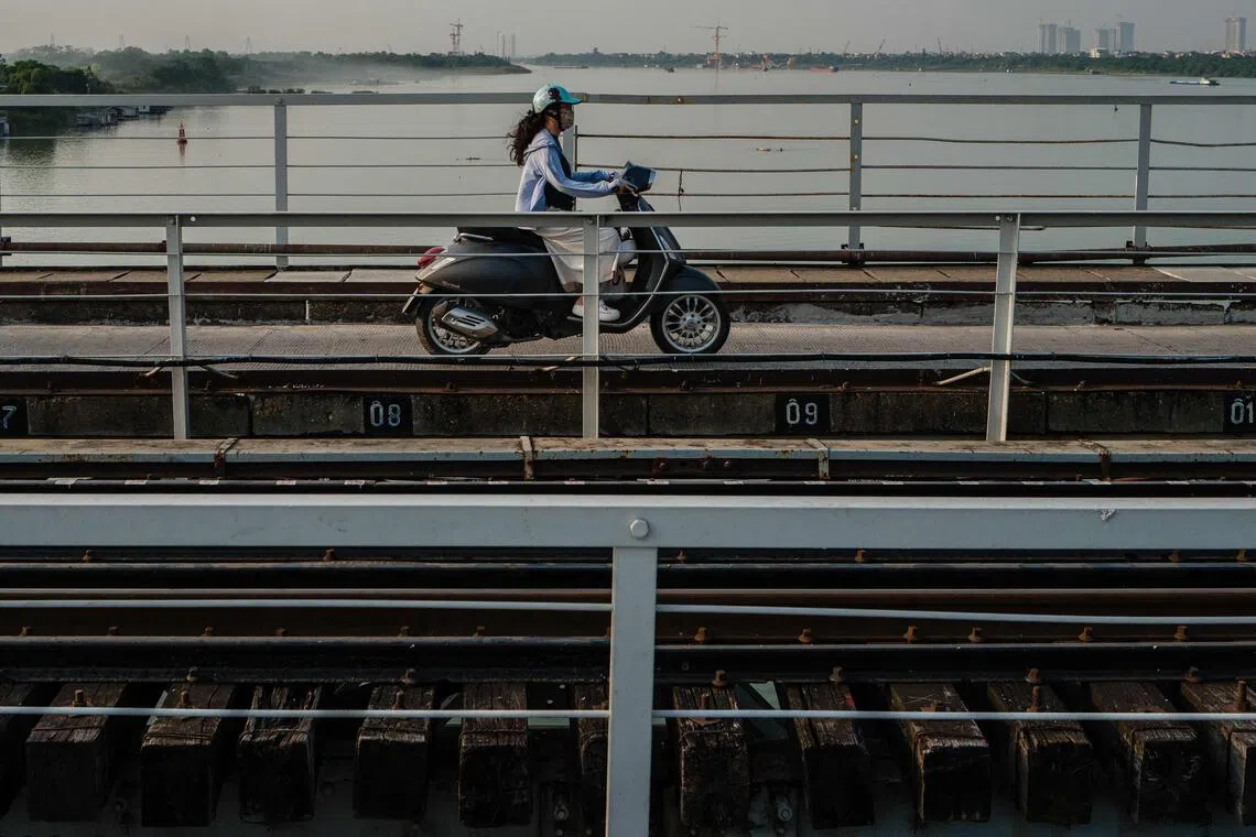 A motorist drives her motorbike on a bridge that runs over the Red River in Hanoi on Oct 23.