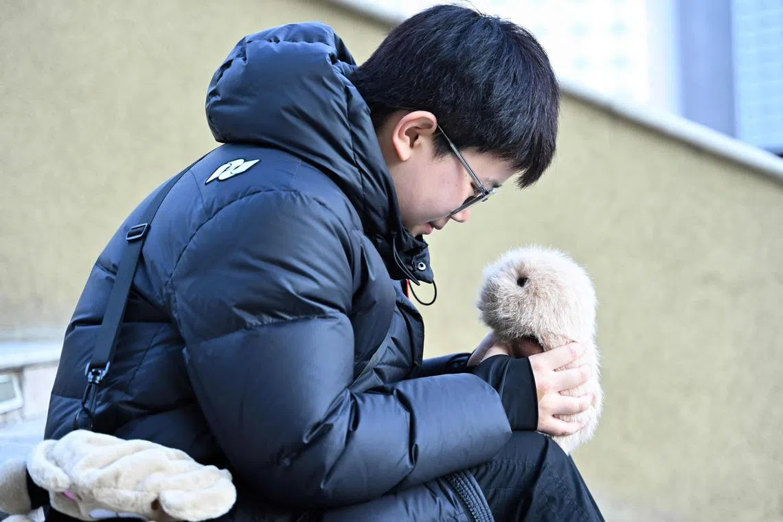 This picture taken on January 7, 2025 shows Zhang Yachun talking to her her AI-powered robot named Aluo at a shopping centre in Beijing. Zhang, 19, has long battled anxiety over school and work, and has struggled to form deep friendships with other people. But since buying a BooBoo -- a "smart pet" that uses artificial intelligence to interact with humans -- she says life has become easier. (Photo by Adek BERRY / AFP) / To go with 'CHINA-AI-SOCIETY-TECHNOLOGY, FOCUS' by Mary Yang, with Emily Wang in Nanjing