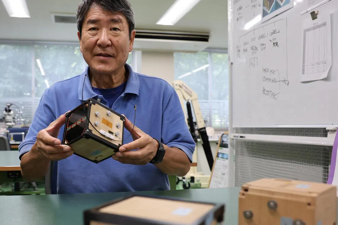 Takao Doi, a former Japanese astronaut and professor at Kyoto University, holds an engineering model of LignoSat at his laboratory at Kyoto University in Kyoto, Japan.