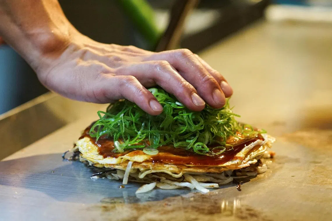 Mr Atsuki Kitaura, manager at okonomiyaki specialty chain Chinchikurin restaurant, prepares okonomiyaki.
