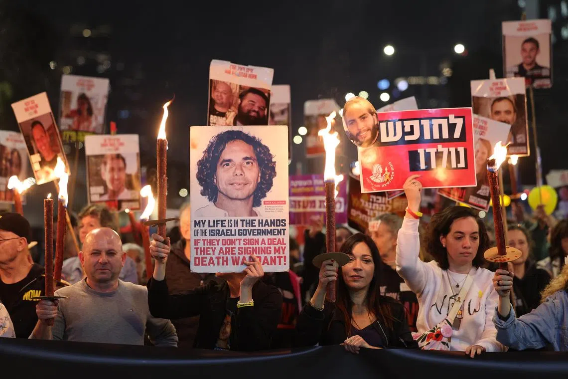 Famiy members of hostages held by Hamas in Gaza and their supporters hold torches and posters calling for a ceasefire and the release of hostages.