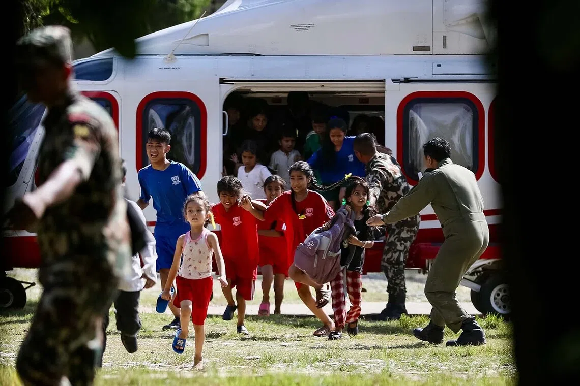 Rescued children disembark from a helicopter at an army camp following flash floods, in Battar Bazar town in Nepal's Nuwakot district on August 28, 2026. Devastating floods on the Nepal-Tibet border region have killed at least 469 people, Nepali police said on August 28, 48 hours after the disaster. (Photo by PRABIN RANABHAT / AFP)