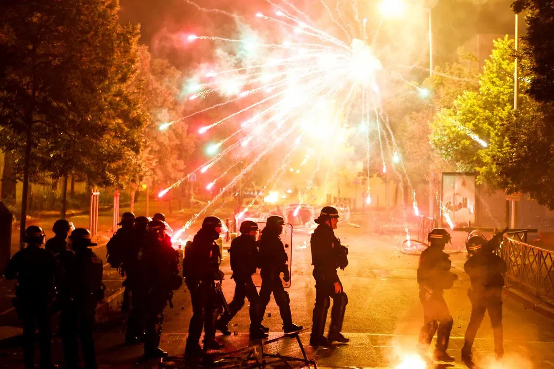 French police stand in position as fireworks go off during clashes with youth, after the death of Nahel, a 17-year-old teenager killed by a French police officer during a traffic stop, in Nanterre, Paris suburb, France, June 30, 2023. REUTERS/Gonzalo Fuentes