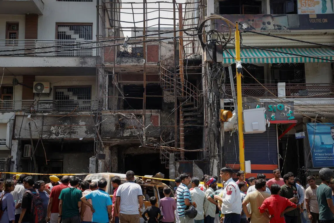 People stand in front of a baby care hospital where several newborns died in a fire, in New Delhi on May 26.