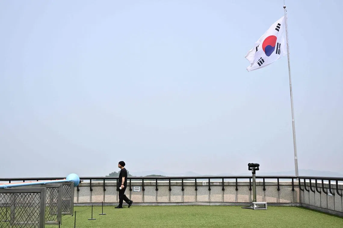 A man walks under South Korea's national flag on a viewing deck where visitors can look towards North Korea (not in frame) at the Odusan Unification Observatory in Paju on June 11, 2024. South Korean troops fired warning shots after North Korean soldiers briefly crossed the border this week, Seoul's military said on June 11, with tensions high over Pyongyang's trash-carrying balloons and the South's retaliatory loudspeaker campaign. (Photo by ANTHONY WALLACE / AFP)