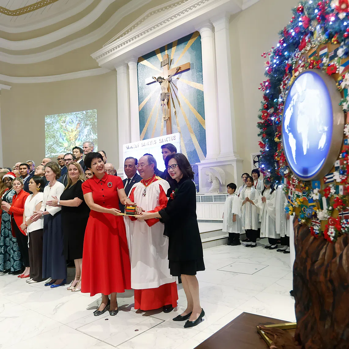 Minister in the ​PMO's office and Second Minister for Finance and National Development​, Ms Indranee Rajah (third from right) pressing a button to light up the symbolic tree of peace with the choir's founder-director Peter Low and his wife Linda. 
PHOTO: CATHEDRAL CHOIR OF THE RISEN CHRIST