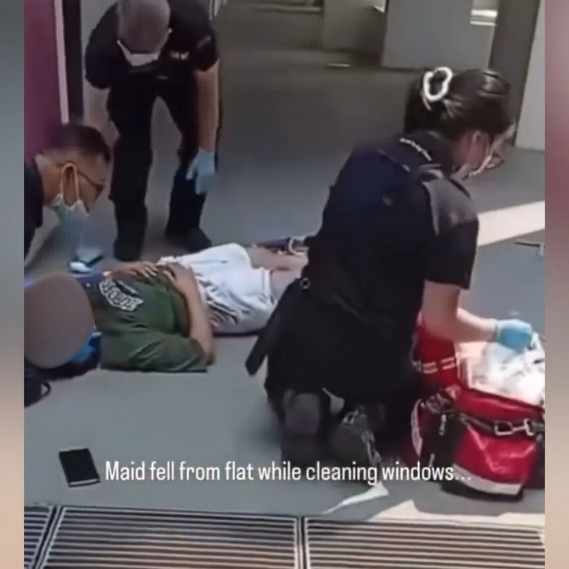 In an online video, a woman is seen lying at the foot of a building with a squeegee nearby.
