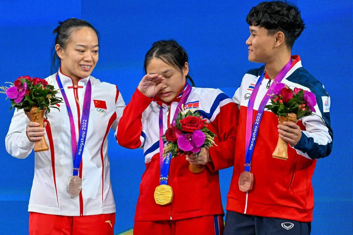 North Korea's Ri Song Gum celebrates after winning the gold medal next to China’s Jiang Huihua and Thailand’s Thanyathon Sukcharoen.