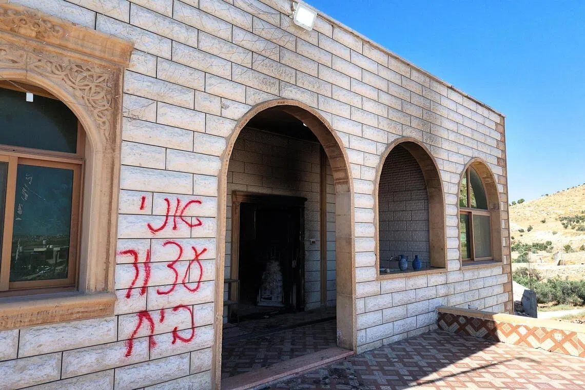 Graffiti spray-painted on the wall of a mosque, which Palestinians say was painted by Israeli settlers, in the Israeli-occupied West Bank on July 19.