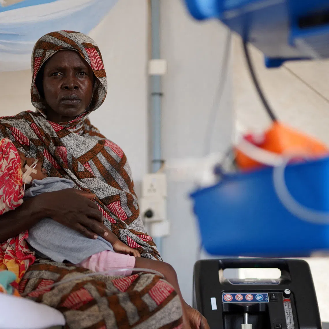 FILE PHOTO: An injured displaced Sudanese woman who fled violence in al-Fashir receives treatment while carrying her child at a makeshift clinic run by Medecins Sans Frontieres (MSF), amid ongoing clashes between the paramilitary Rapid Support Forces (RSF) and the Sudanese army, in Tawila, North Darfur, Sudan November 3, 2025. REUTERS/Mohamed Jamal/File Photo