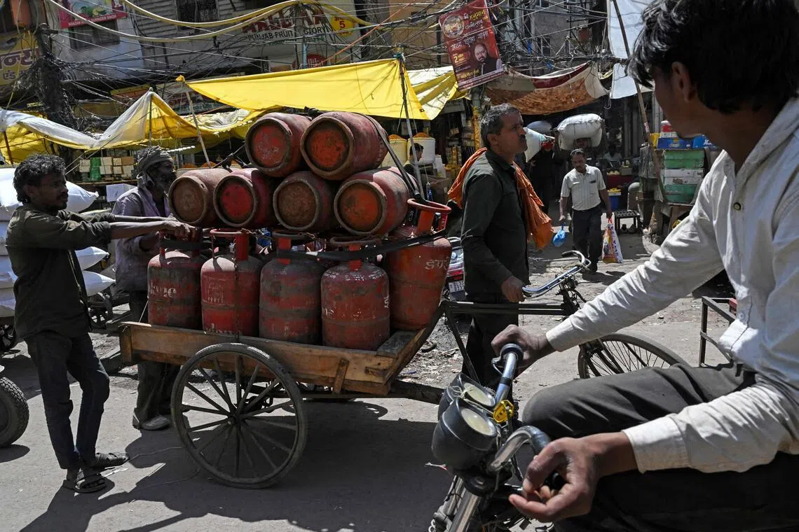 Workers transport liquefied petroleum gas (LPG) cylinders on a rickshaw for distribution at a spice market in the old quarters of Delhi on April 10, 2026.