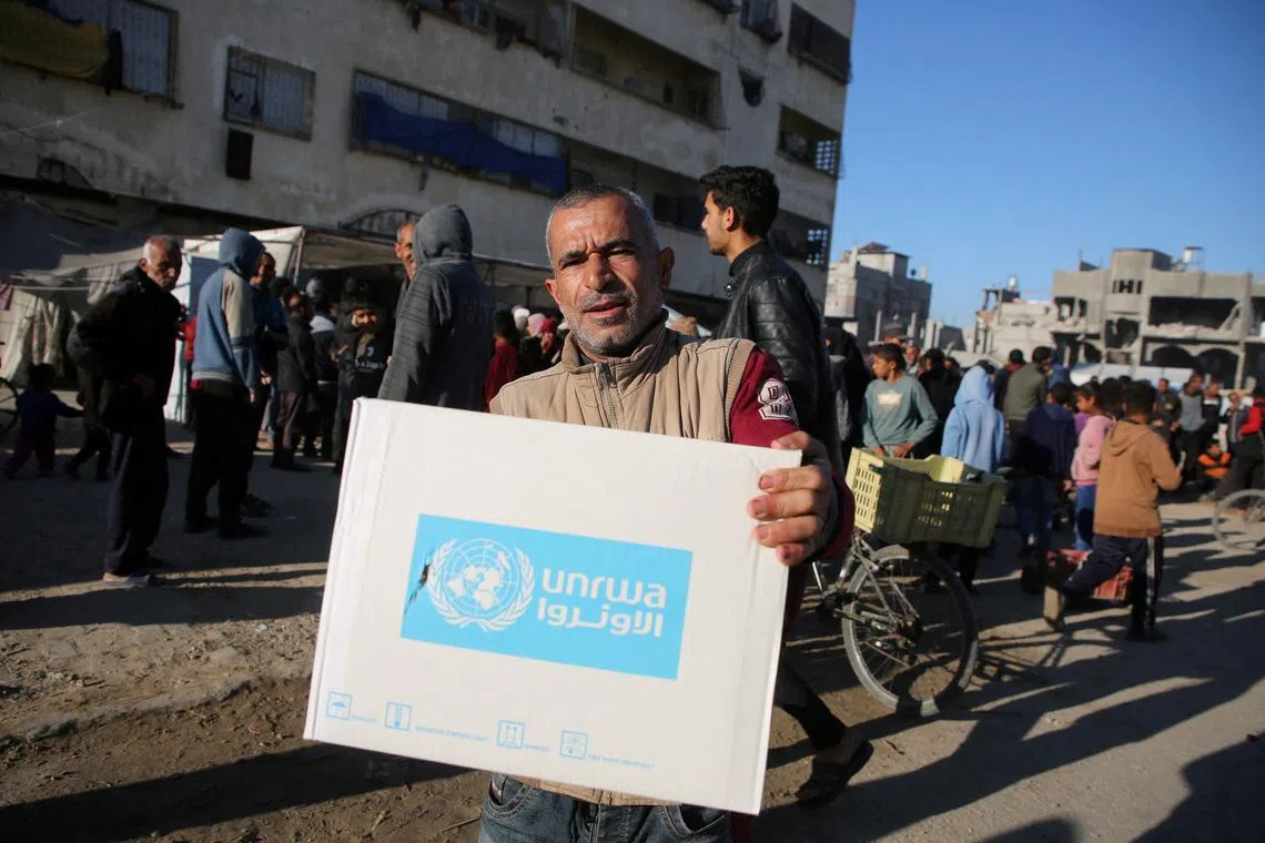 FILE PHOTO: A Palestinian man carries an aid box provided by UNRWA, following a ceasefire between Israel and Hamas, in Khan Younis in the southern Gaza Strip, January 21, 2025. REUTERS/Hatem Khaled/File Photo
