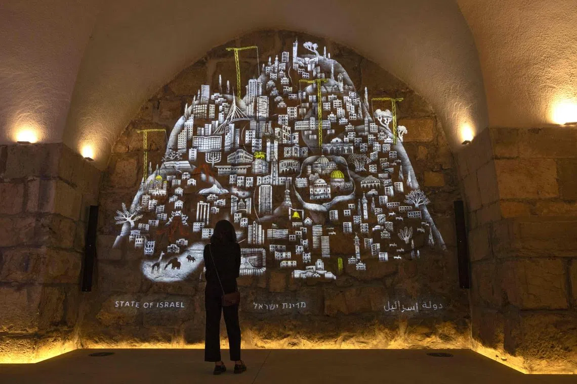A visitor looking at a video animation showing some of Jerusalem's history, made by Israeli film director Ari Folman, projected on a wall in the Tower of David Museum in Jerusalem's Old City, on May 30 2023. The newly designed Tower of David Museum will be open after a three-year renovation project. 