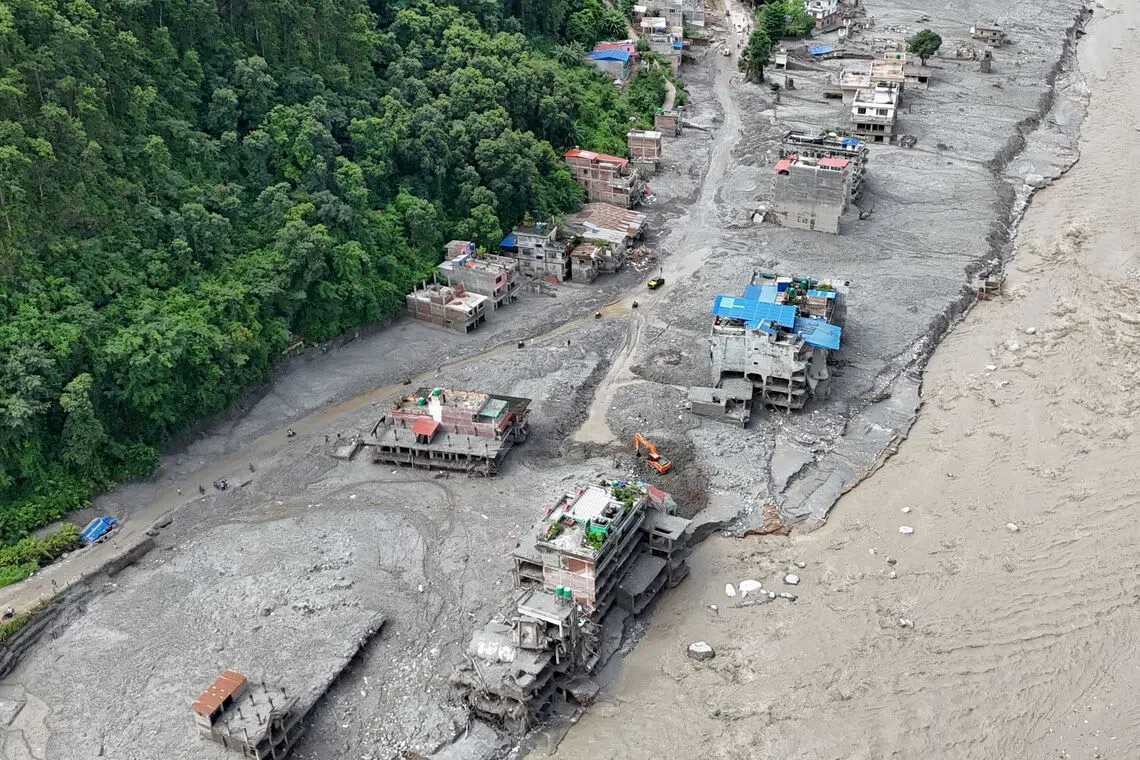 An aerial view shows a torrent of muddy water surging past houses and through the Trishuli River in the aftermath of flash floods in Nepal’s Nuwakot district on Sept 1.
