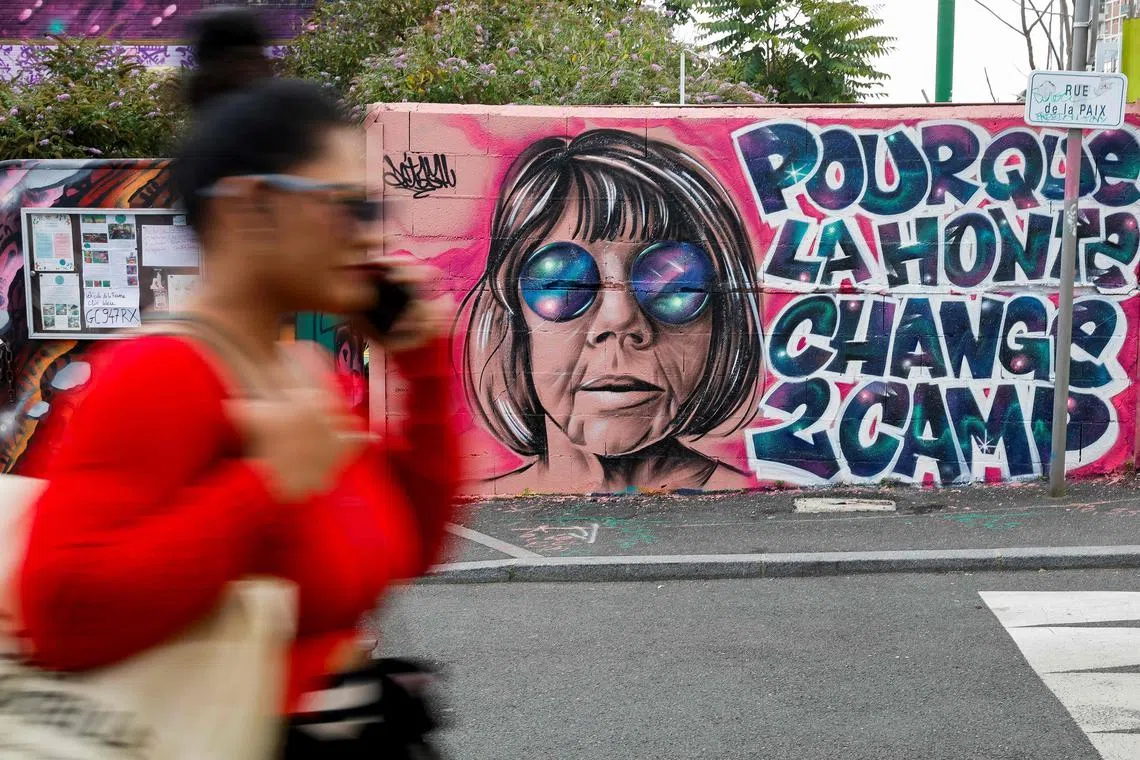 TOPSHOT - A woman walks past a mural created by Maca_dessine depicting Gisele Pelicot and a sentence reading "So that shame changes sides" in Gentilly, south of Paris on September 21, 2024 as her former partner Dominique Pelicot is accused of drugging her for nearly ten years and inviting strangers to rape her at their home in Mazan. A court in the southern town of Avignon is trying Dominique Pelicot, a 71-year-old retiree, for repeatedly raping and enlisting dozens of strangers to rape his heavily sedated wife in her own bed over a decade. Fifty other men, aged between 26 and 74, are also on trial for alleged involvement, in a case that has horrified France. The court proceedings, which runs until December, are open to the public at the request of Dominique Pelicot's ex-wife and victim. (Photo by GEOFFROY VAN DER HASSELT / AFP) / RESTRICTED TO EDITORIAL USE - MANDATORY MENTION OF THE ARTIST UPON PUBLICATION - TO ILLUSTRATE THE EVENT AS SPECIFIED IN THE CAPTION
