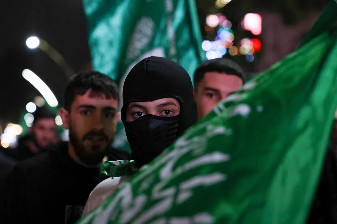 A masked man carries the flag of the Palestinian Hamas movement during a march in the occupied West Bank city of Hebron, to express solidarity with the Gaza Strip.