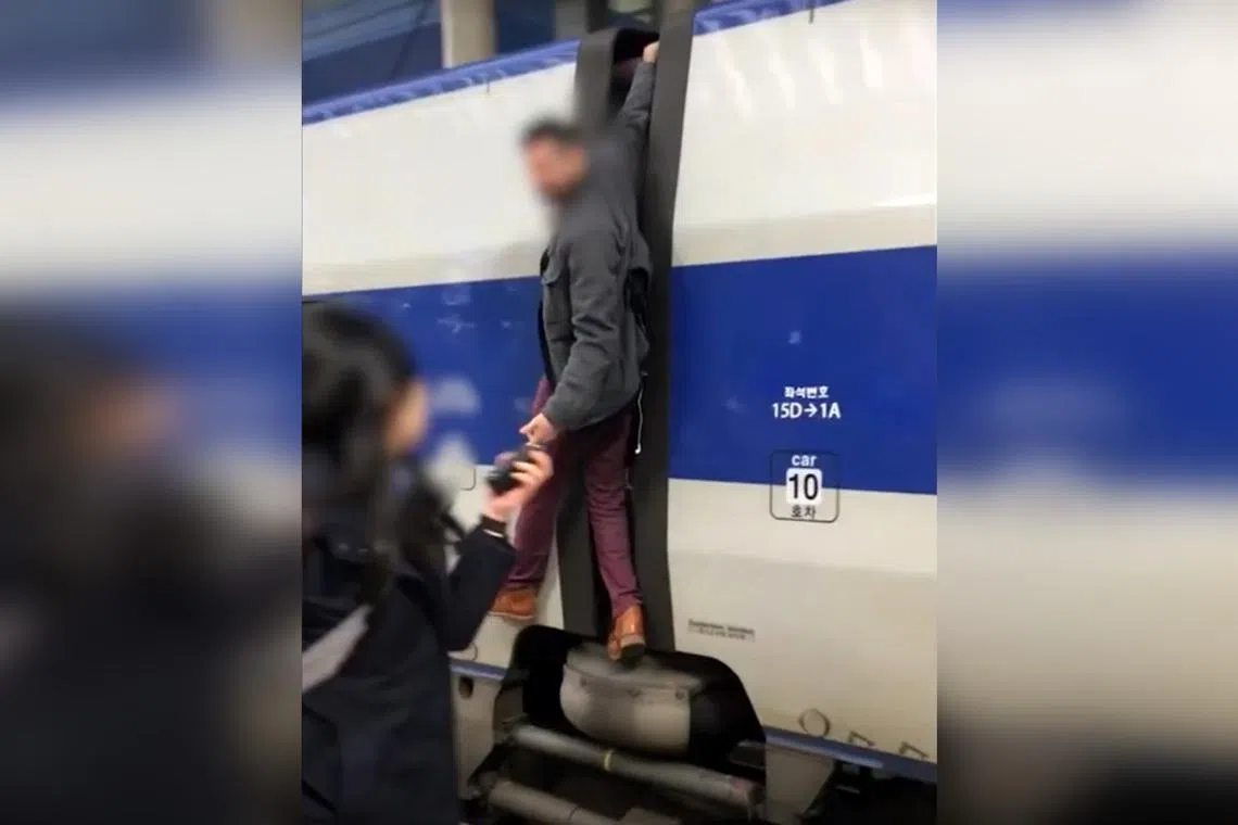 In the video, the man is seen holding onto the train with one arm while shouting at a train employee to stop the train.