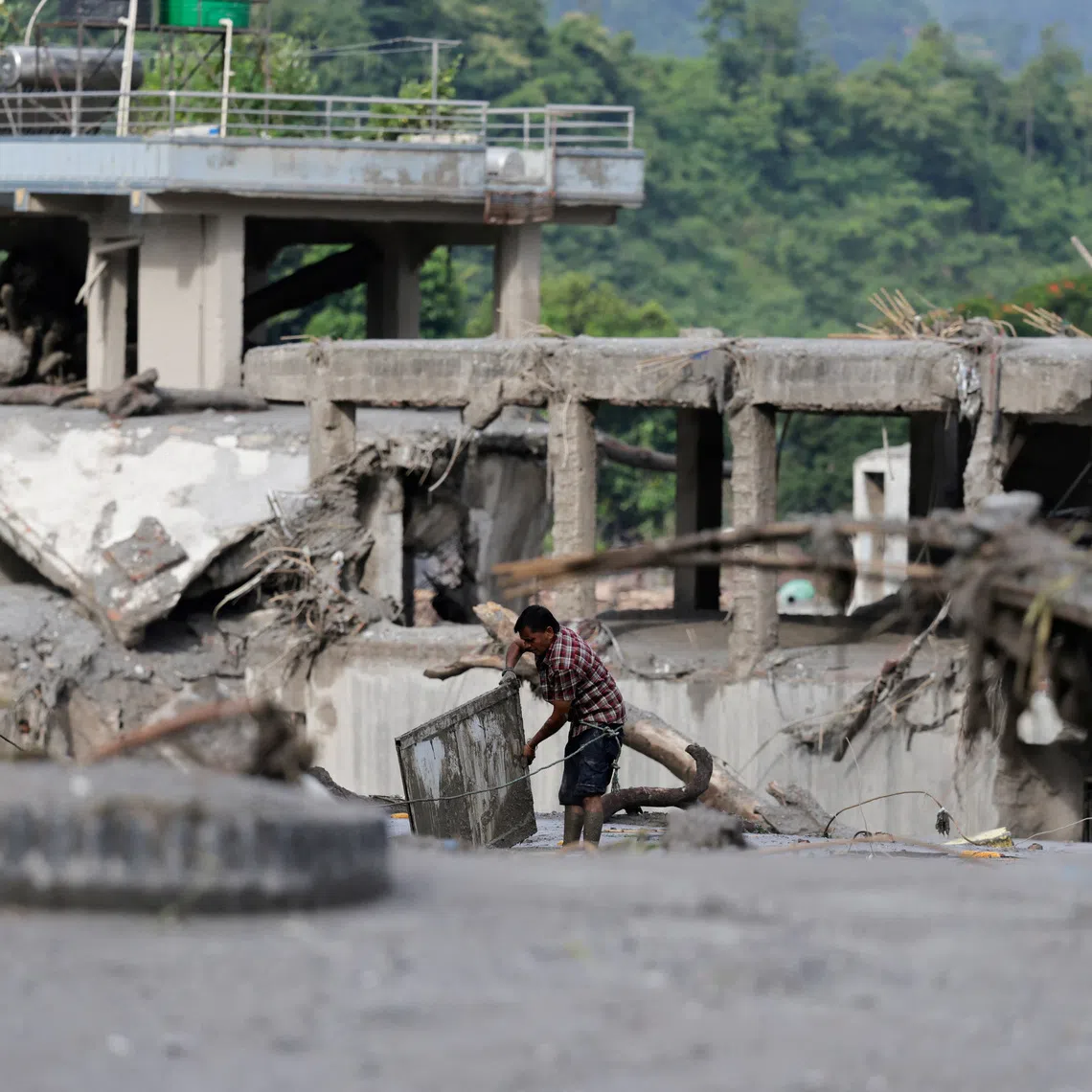 A man salvages his belongings from mud following devastating floods, in Trishuli in Nuwakot district, Nepal, August 27, 2026. REUTERS/Navesh Chitrakar