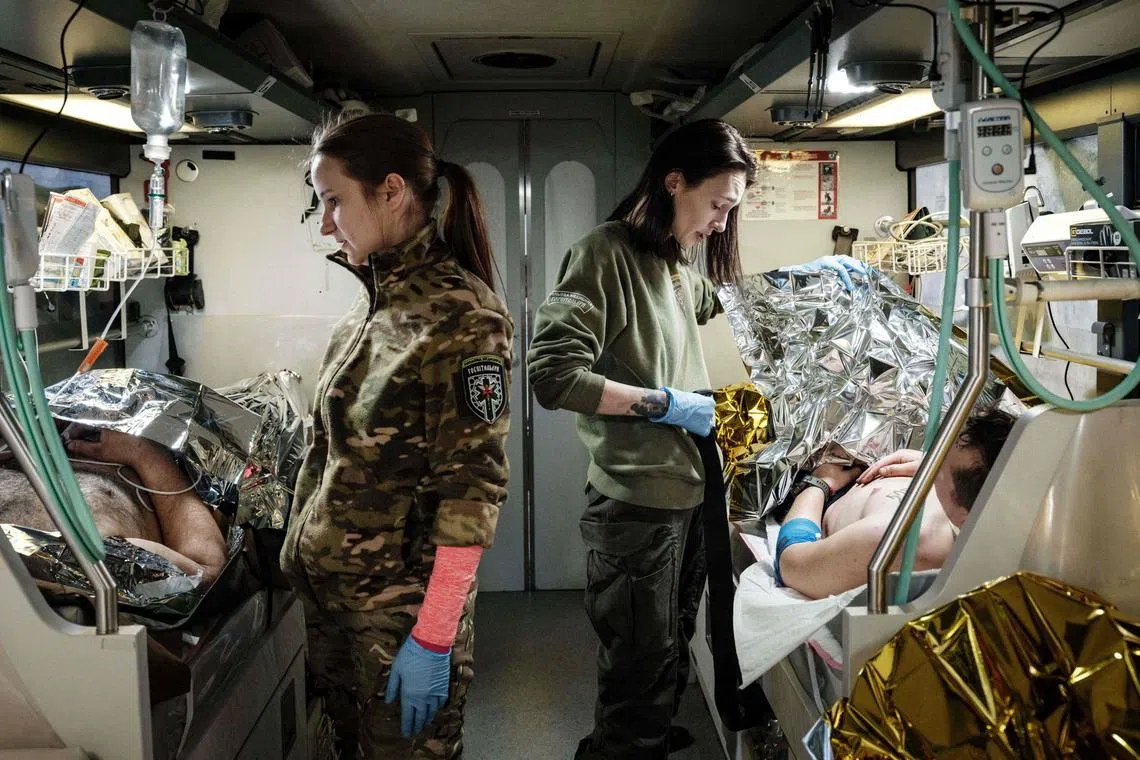 Ukrainian Poet Olena Herasymyuk (R) and Anna Skolbushevska are seen during their work as paramedics for the volunteer medical battalion Hospitallers, which helps with medical evacuations of wounded Ukrainian servicemen, on their medical evacuation bus in Donetsk region on February 11, 2023, amid the Russian invasion of Ukraine. - The medical evacuation bus called "Austrian” was named after the call sign of the Ukrainian doctor Natalia Frauscher who lived in Austria and died in a traffic accident during her duty on the previous medical evacuation bus last June. (Photo by YASUYOSHI CHIBA / AFP)