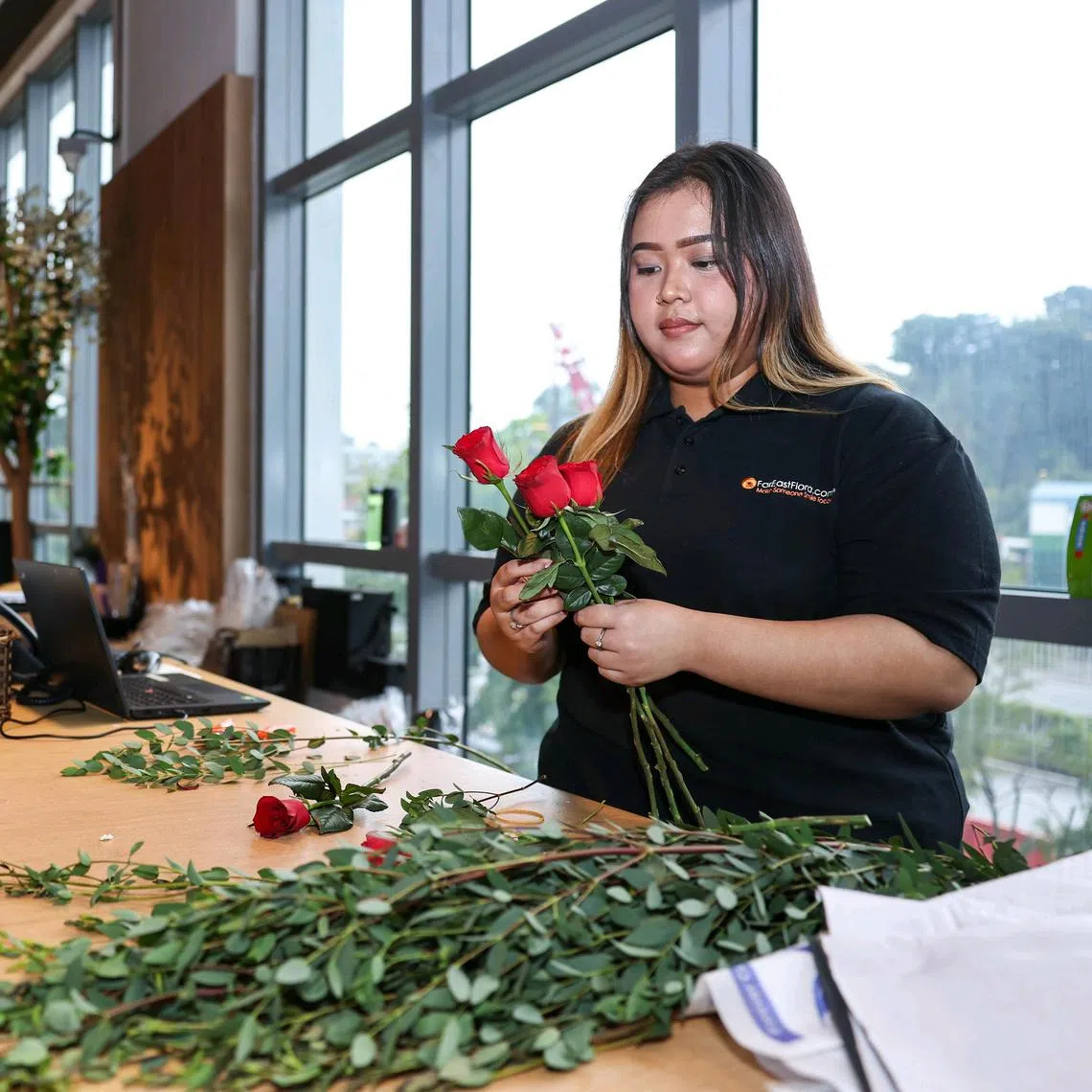 Ms Arfah Mohamad Nasir, 23, working on a flower bouquet at the Far East Flora Centre. Lower-wage resident retail workers can expect an annual salary bump from Sept 1.