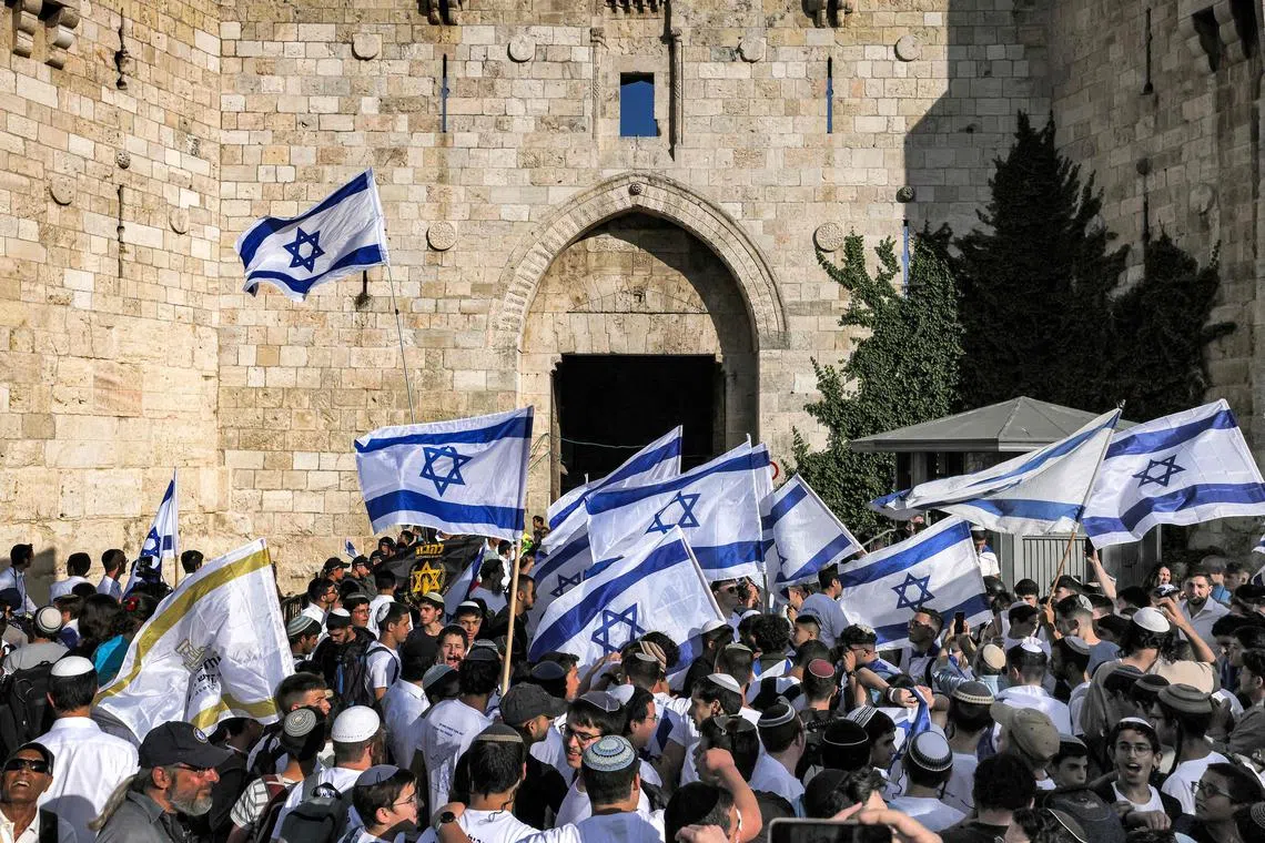 Demonstrators waving Israeli flags gather outside the Damascus Gate of the Old City of Jerusalem during the annual flag march to mark Jerusalem Day.