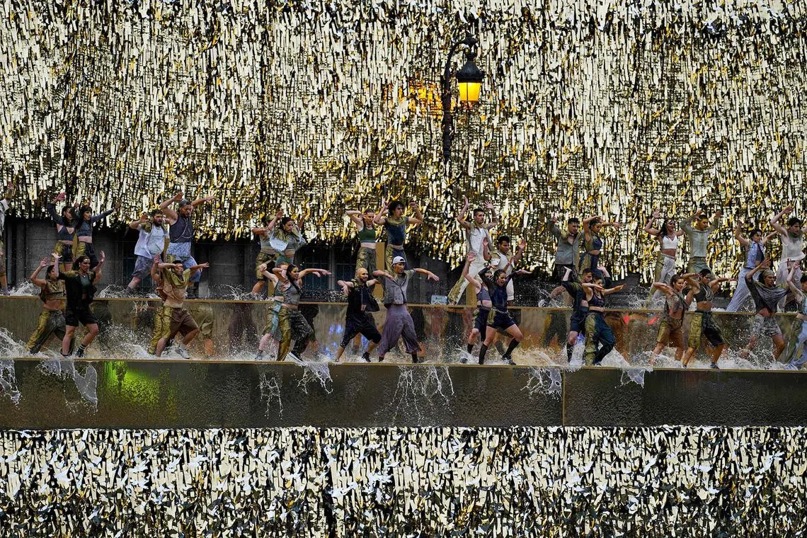 TOPSHOT - Performers dance along the banks of the Seine River during the opening ceremony of the Paris 2024 Olympic Games in Paris on July 26, 2024. (Photo by Petros Giannakouris / POOL / AFP)