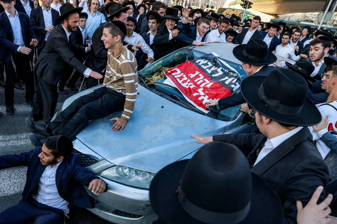 A driver using his vehicle and attempting to break through a blockade by ultra-Orthodox Jewish protesters gathering for a demonstration against conscription by the Chords Bridge of the Jerusalem Light Rail in Jerusalem on July 23, 2025. 