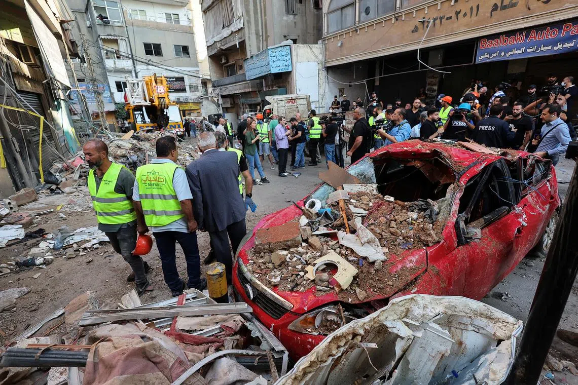 People stand next to a destroyed car, at the site of an Israeli strike in Beirut's southern suburbs, Lebanon September 24, 2024. REUTERS/Amr Abdallah Dalsh