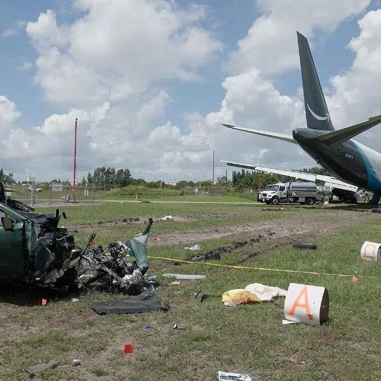 A damaged car next to the wreckage of an Amazon Prime Air cargo plane that overran a runway at Miami International Airport.