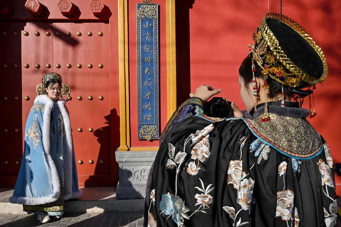 TOPSHOT - Women dressed in imperial costumes take photographs outside a temple next to the Nanluoguxiang alleyway in Beijing on January 6, 2025. (Photo by Adek BERRY / AFP)