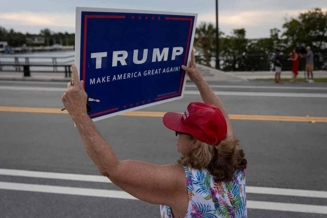 A supporter holds a placard following the announcement of the verdict in former U.S. President Donald Trump's criminal trial over charges that he falsified business records to conceal money paid to silence porn star Stormy Daniels in 2016, outside former U.S. President Donald Trump’s Mar-a-Lago resort in Palm Beach, Florida, U.S., May 30, 2024. REUTERS/Marco Bello/ File Photo