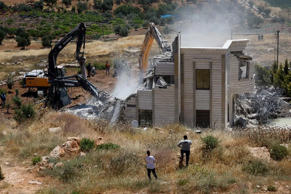 Palestinians observe, as heavy machinery demolishes a Palestinian house near Hebron, in the Israeli-occupied West Bank, June 8, 2026. REUTERS/Mussa Qawasma