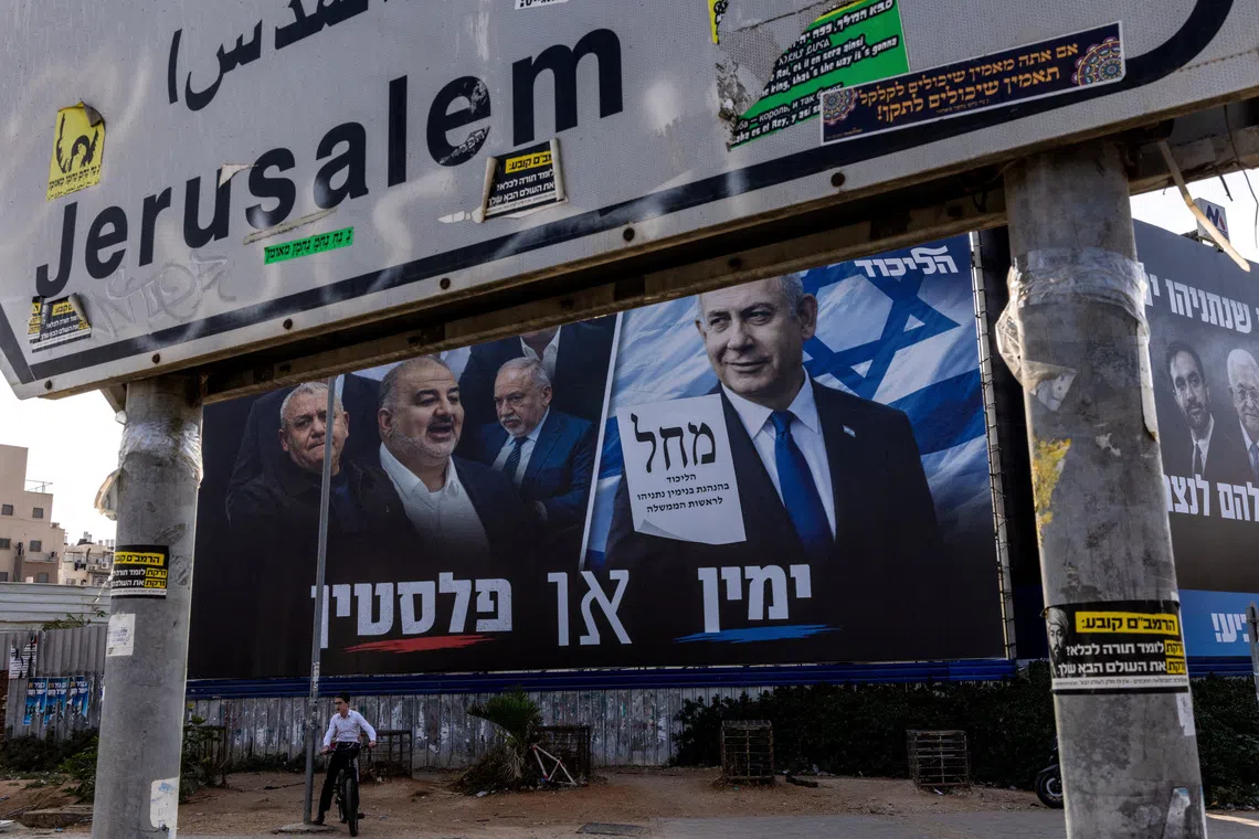 A boy sits on his bicycle next to a campaign banner of Netanyahu’s Likud party on Oct 25, ahead of the Israeli parliamentary election, in Bnei Brak, Israel.