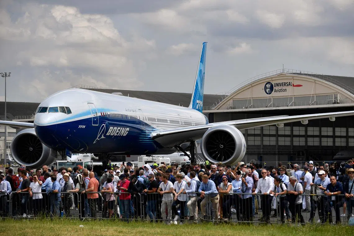 This photograph taken on June 21, 2023 shows attendees lined up along barriers in front of a Boeing 777 aeroplane to watch demonstration flights displayed during the International Paris Air Show at the Paris�Le Bourget Airport. (Photo by JULIEN DE ROSA / AFP)