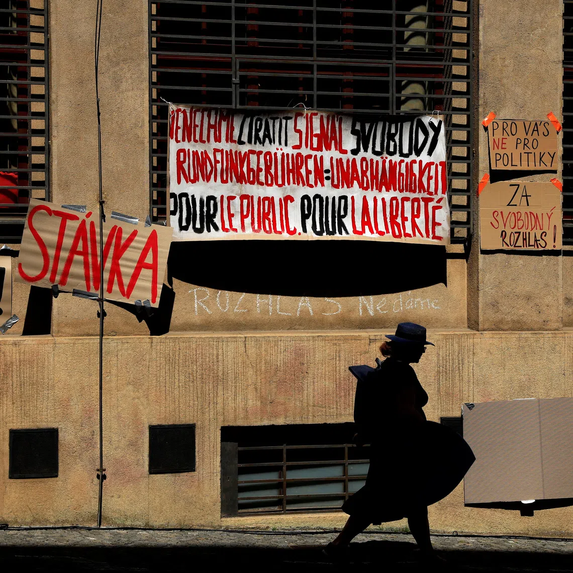 FILE PHOTO: A woman walks past placards hanging on a building of Czech Radio as employees of public broadcasters strike in protest of the government's planned overhaul of public media funding, in Prague, Czech Republic, June 22, 2026. REUTERS/David W Cerny/File Photo
