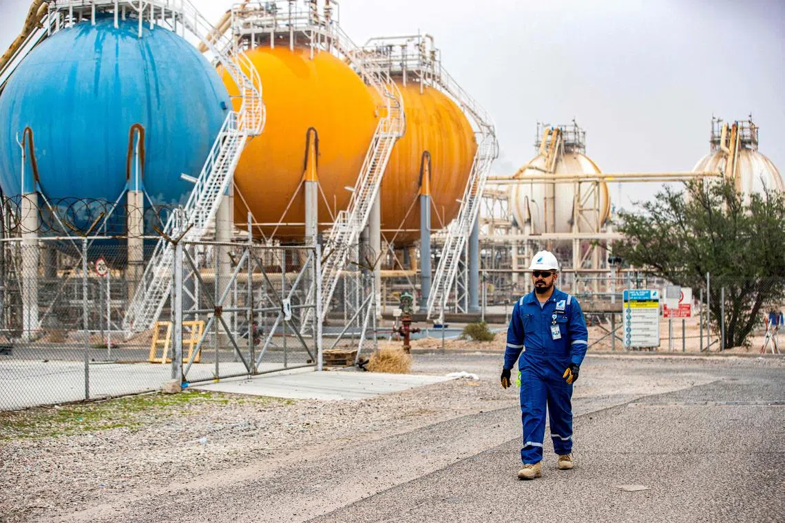 An engineer walks past tanks at the gas liquefaction plant of the Basra Gas Company (BGC) at its headquarters in Iraq's southern city of Basra on December 13, 2023. (Photo by Hussein Faleh / AFP)