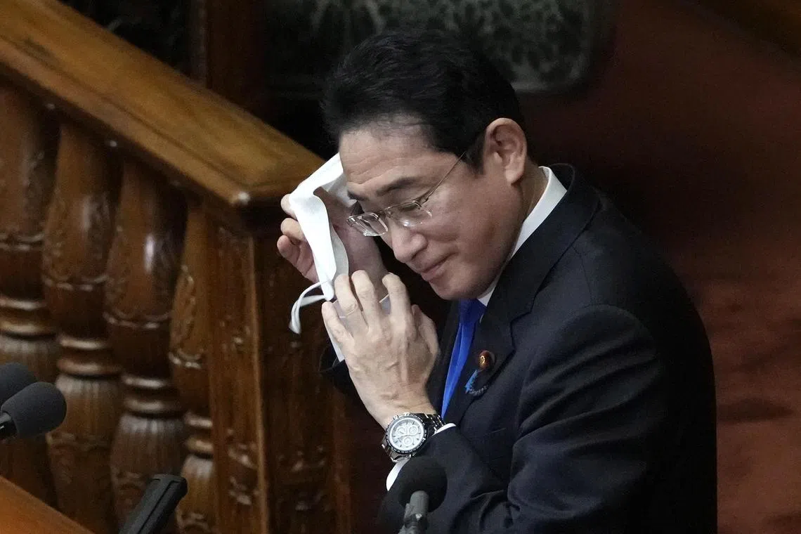 Japan's Prime Minister Fumio Kishida takes off his face mask before delivering his policy speech at the start of an ordinary session of the Diet on Monday Jan 23.