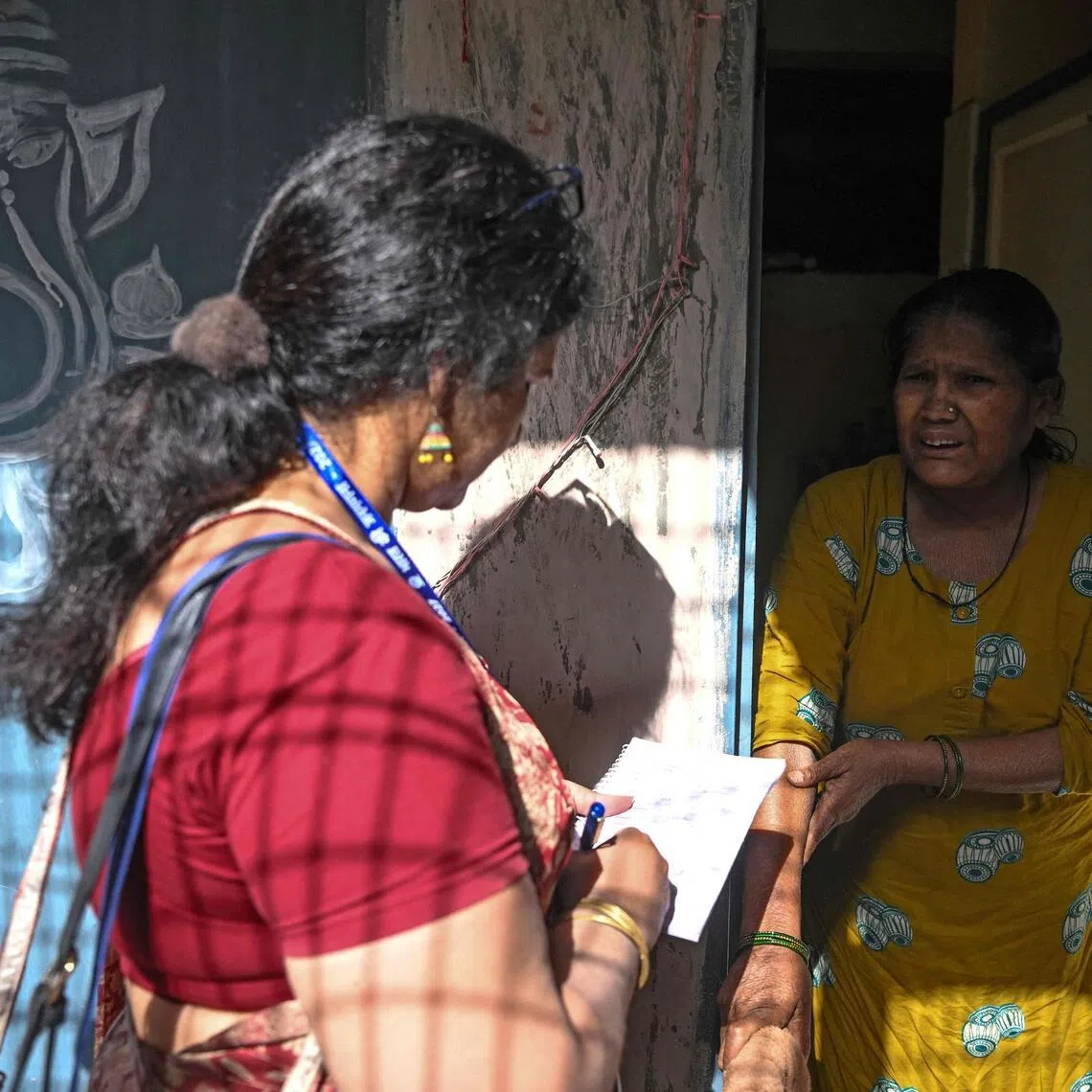 Sukhwinder Kaur, a census enumerator and a school teacher, collects details of housing and amenities during a door-to-door survey in the first phase of the census at a residential area in New Delhi.