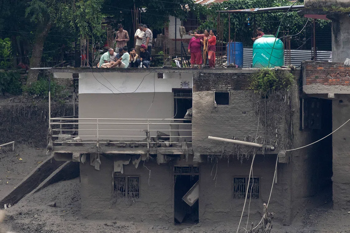 epa13193007 Locals take refuge on a rooftop as floodwaters sweep through Trishuli Bazar following a flash flood, in Nuwakot district, Nepal, 26 August 2026. Several people were killed and multiple others were reported missing after a massive flash flood swept through Rasuwa and Nuwakot districts causing widespread destruction to settlements and infrastructure, according to local authorities. EPA/NARENDRA SHRESTHA