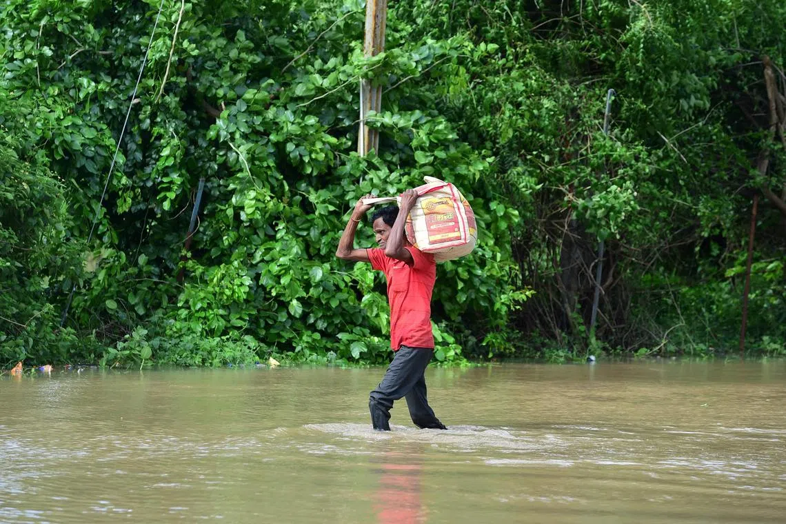 A man carries his belongings through a flooded street after heavy rains on the outskirts of Ahmedabad.