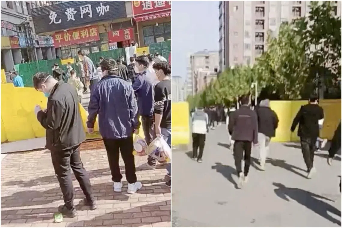 People crossing a fence that has been pulled down following a protest at the Foxconn plant in Zhengzhou, China, on Nov 23, 2022.