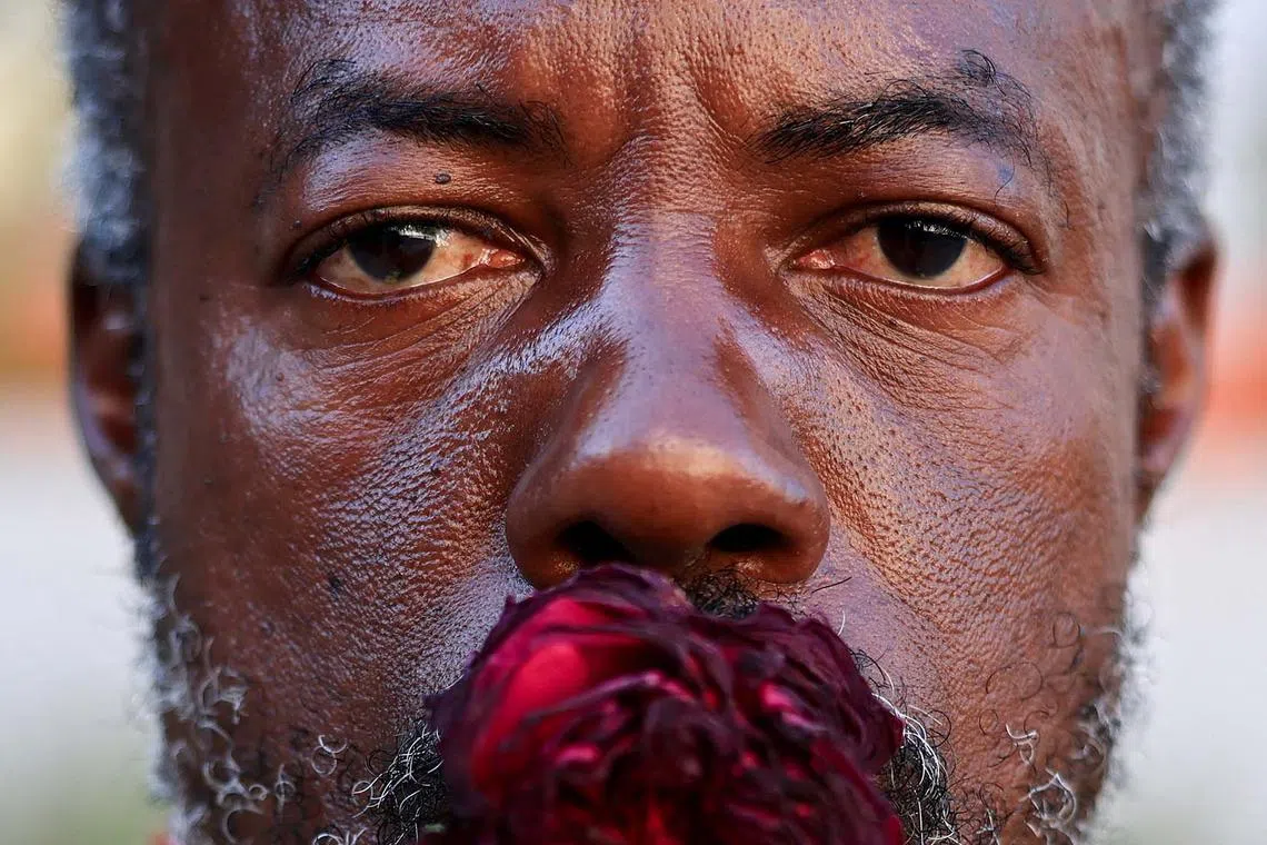 A man, with a flower in his mouth, posing for a photo as Black Lives Matter activists and supporters gather to mark the fifth anniversary of the May 25, 2020 Minneapolis murder of George Floyd, in Los Angeles, California, US, May 21, 2025. 