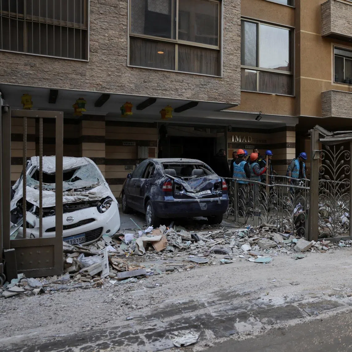 People stand near debris and damaged vehicles at the site of an Israeli strike on an apartment building, in central Beirut, Lebanon, March 11, 2026, following an escalation between Hezbollah and Israel amid the U.S.-Israeli conflict with Iran.