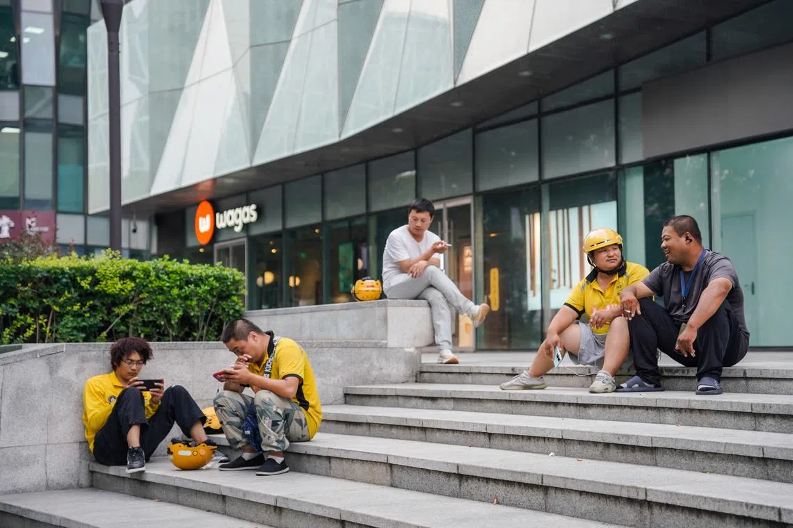 Delivery men sit in front of a shopping mall in Beijing, on Aug 23.