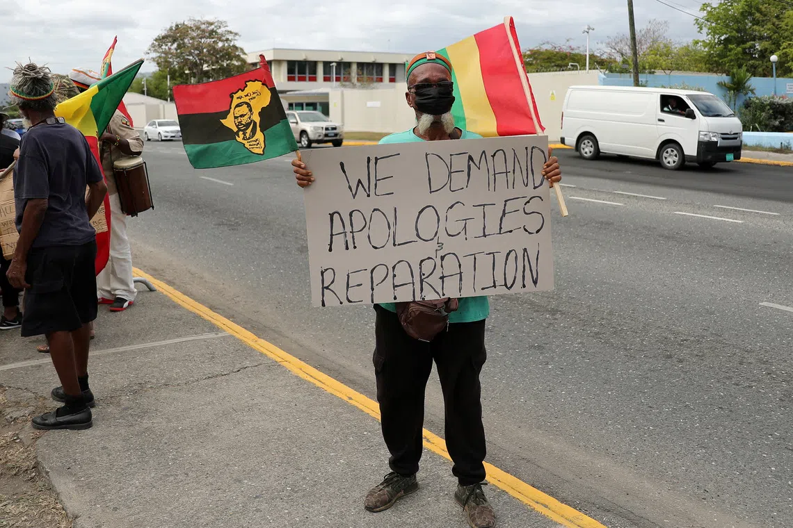 FILE PHOTO: A protester holds a sign during a rally to demand that the United Kingdom make reparations for slavery, ahead of a visit to Jamaica by the Duke and Duchess of Cambridge as part of their tour of the Caribbean, outside the British High Commission, in Kingston, Jamaica March 22, 2022. REUTERS/Gilbert Bellamy/File Photo