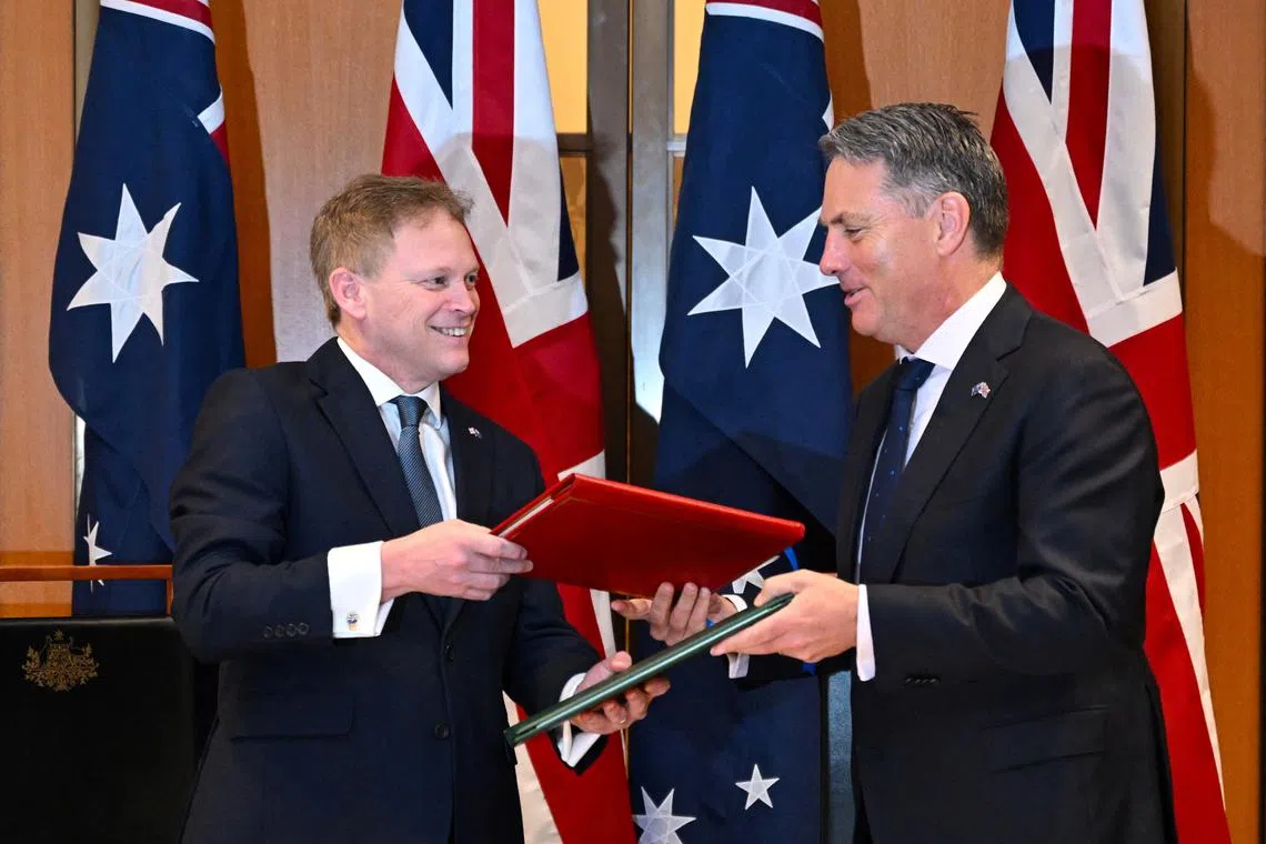 Secretary of State for Defence of the United Kingdom Grant Shapps (L) and Australian Defence Minister Richard Marles exchange Defence Treaty documents during a meeting at Parliament House in Canberra, March 21, 2024. AAP Image/Lukas Coch via REUTERS