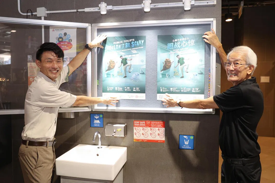 Senior Parliamentary Secretary for Sustainability and the Environment Baey Yam Keng and Public Hygiene Council chairman Edward D’Silva putting up posters for NEA's clean public toilets campaign at the Our Tampines Hub hawker centre on Wednesday.