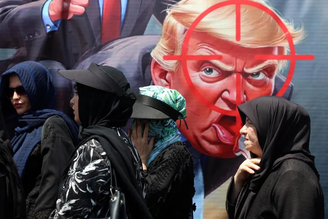 Iranians walk next to an anti-Trump banner in the streets of Tehran.