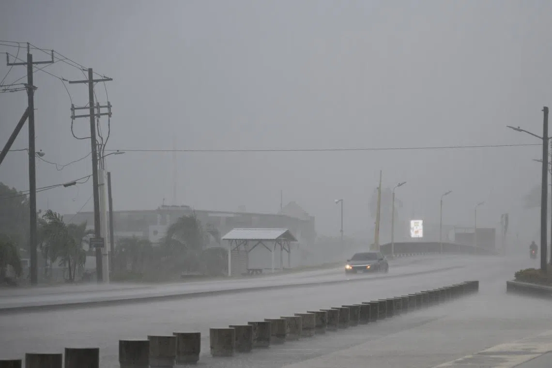 Vehicles make their way through a flooded street before the arrival of Hurricane Lisa in Belize City on Nov 2, 2022.