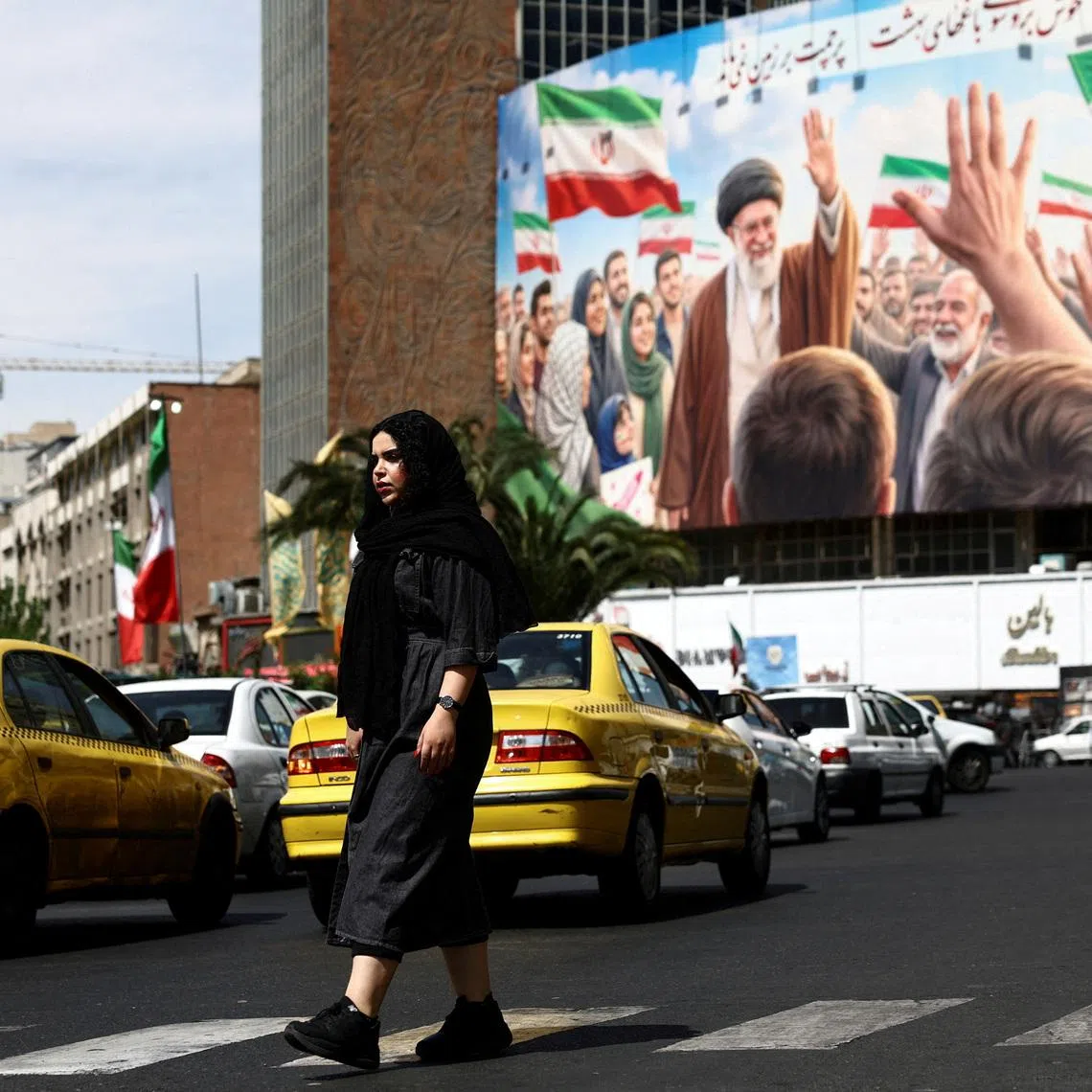 A woman walks past a billboard featuring an image of the late Supreme Leader of Iran, Ayatollah Ali Khamenei, on a building, amid a ceasefire between U.S. and Iran, in Tehran, Iran, April 27, 2026. Majid Asgaripour/WANA (West Asia News Agency) via REUTERS